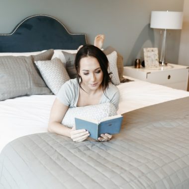 Woman Laying On Bed Reading Book